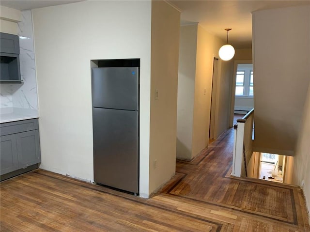 kitchen featuring hardwood / wood-style floors, decorative light fixtures, stainless steel refrigerator, and a baseboard heating unit