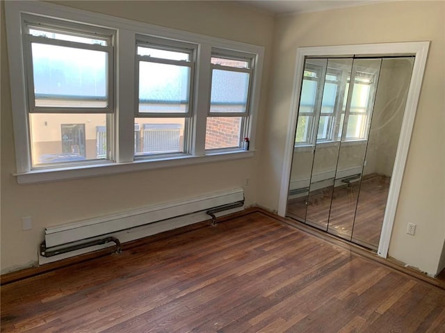 unfurnished room featuring wood finished floors and a baseboard heating unit