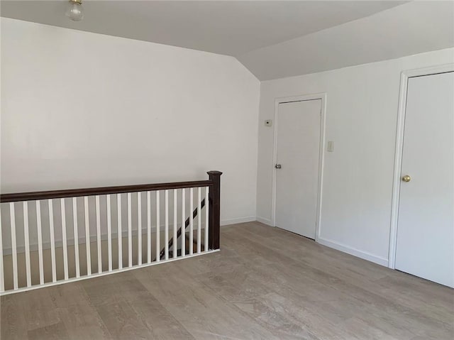 spare room featuring light wood-type flooring and lofted ceiling