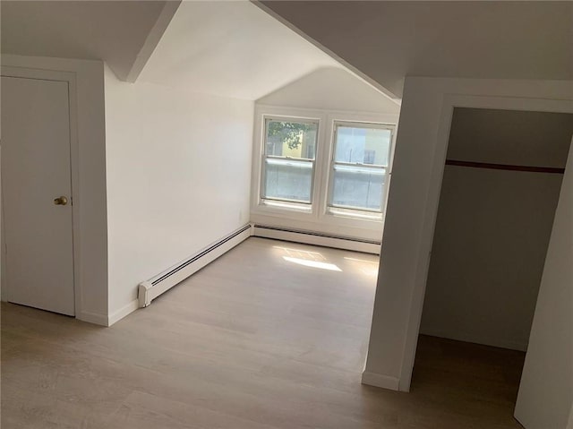 additional living space featuring light wood-type flooring, vaulted ceiling, and baseboard heating