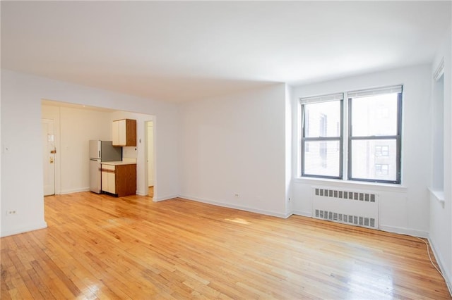 15 Oliver St Unit 4C, Brooklyn, NY 11209 - spare room with radiator, light wood-style floors, and baseboards
