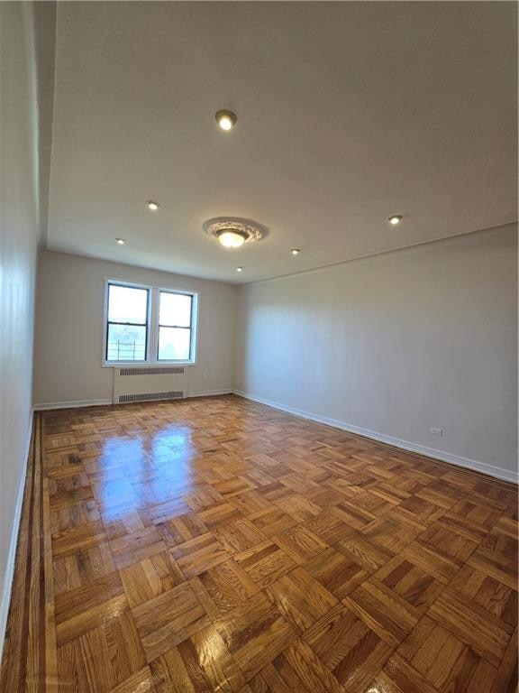 empty room with radiator, baseboards, and recessed lighting