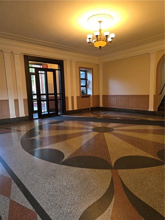 common area featuring ornamental molding, a decorative wall, and a wainscoted wall