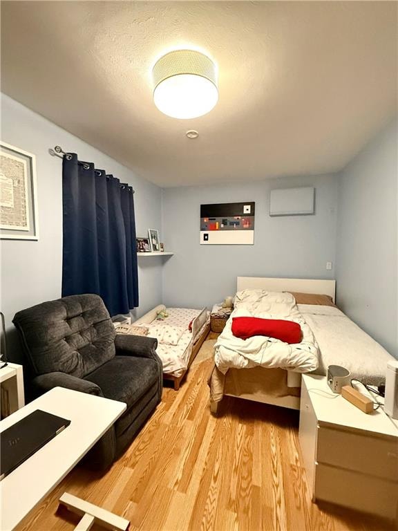 bedroom with light wood-type flooring and a wall unit AC