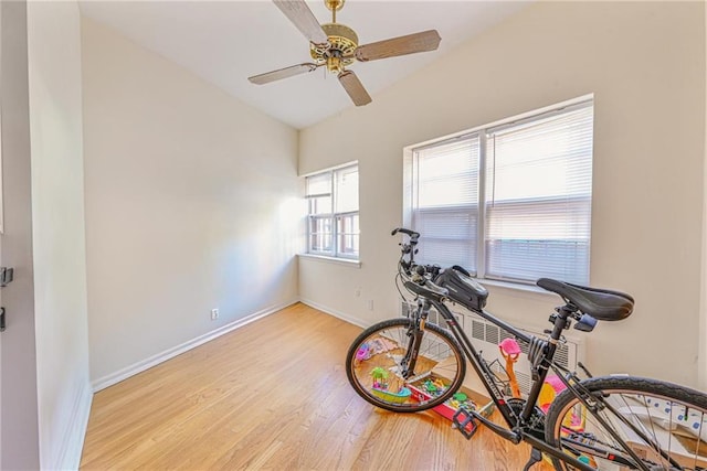 exercise area with baseboards, a ceiling fan, and light wood-style floors