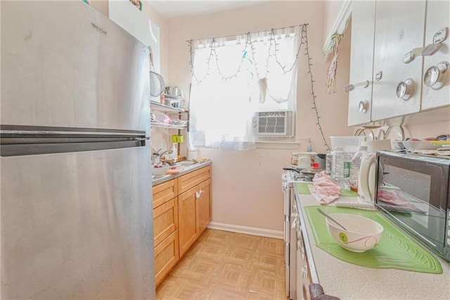 kitchen with baseboards, light countertops, cooling unit, and freestanding refrigerator