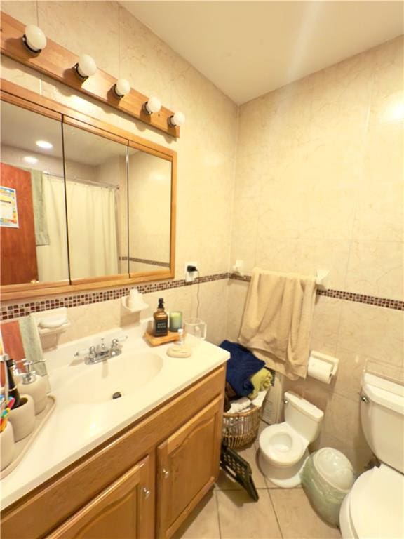 bathroom featuring tile walls, toilet, vanity, a shower with curtain, and tile patterned floors