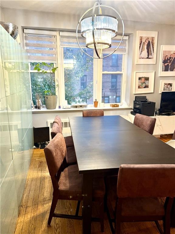 dining room featuring wood finished floors, visible vents, and an inviting chandelier