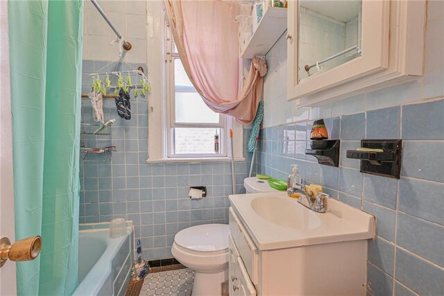 full bathroom with tile patterned floors, toilet, tile walls, vanity, and shower / bathtub combination with curtain