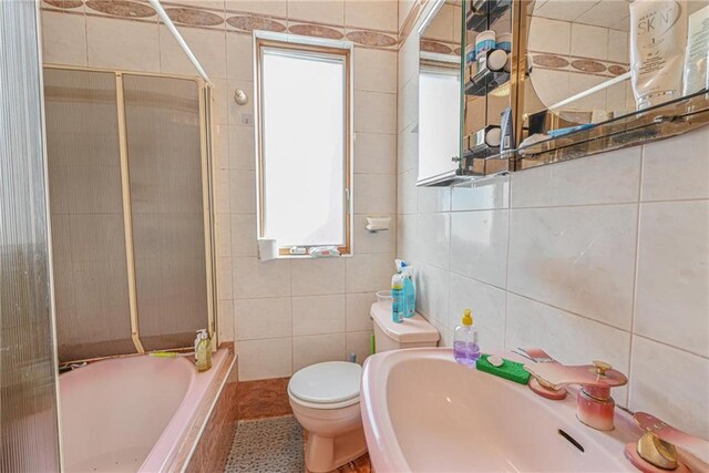 full bathroom featuring tile walls, sink, toilet, and tiled shower / bath