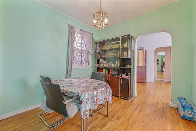 dining room featuring a chandelier, arched walkways, wood-type flooring, and ornamental molding