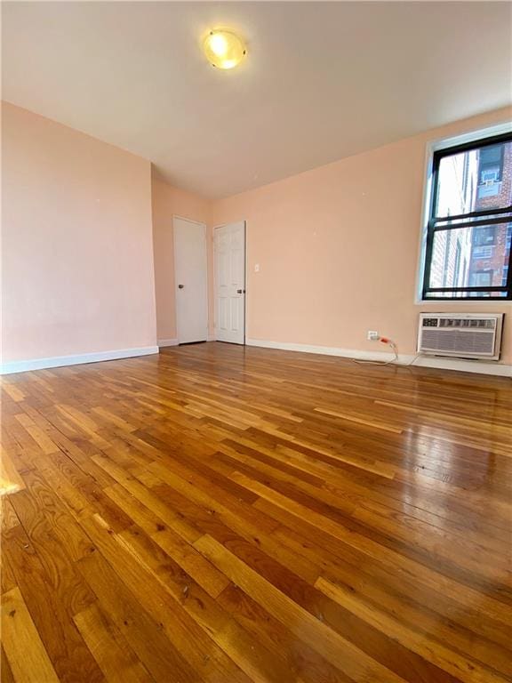 spare room with a wall mounted AC and hardwood / wood-style flooring