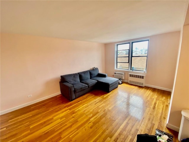 living room with a wall unit AC, radiator heating unit, and wood-type flooring