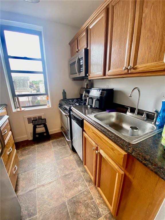 kitchen featuring dark stone countertops, appliances with stainless steel finishes, and sink