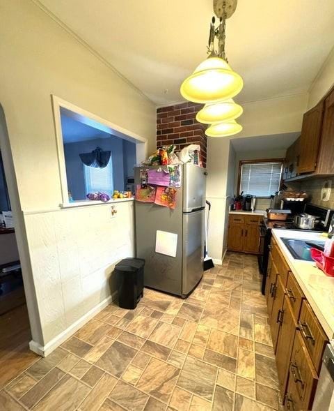 kitchen with sink, white range with electric cooktop, hanging light fixtures, and stainless steel refrigerator