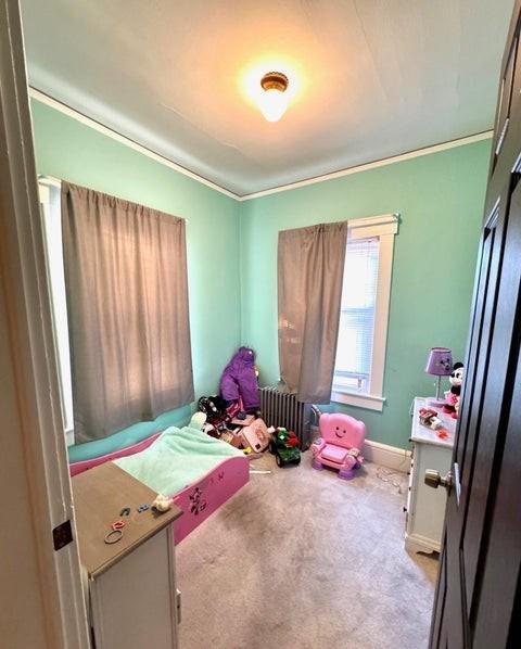 bedroom featuring light carpet, crown molding, and radiator