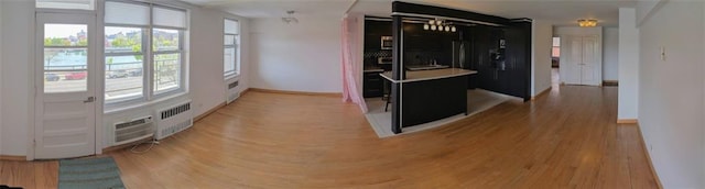 hall with light wood finished floors, radiator heating unit, baseboards, and an AC wall unit