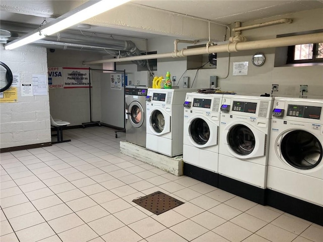 clothes washing area featuring light tile patterned floors and washer and dryer