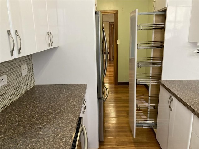 kitchen featuring stainless steel fridge, white cabinetry, and backsplash