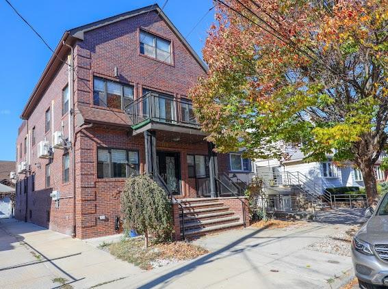 view of front of home featuring brick siding and a balcony