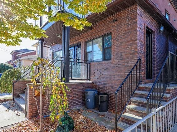 view of side of property with stairs and brick siding