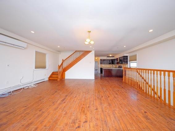 unfurnished living room with hardwood / wood-style floors and an AC wall unit