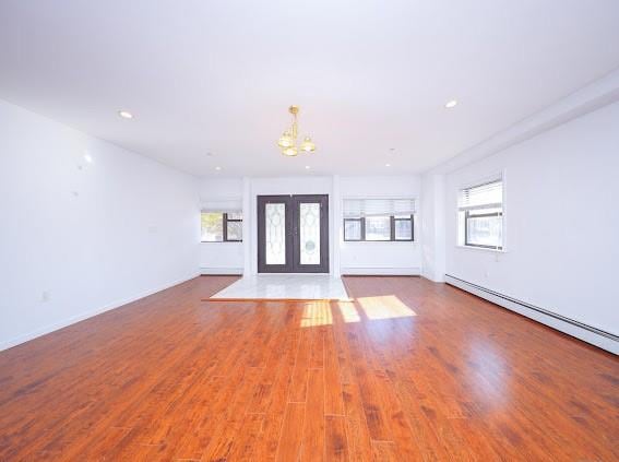 interior space featuring french doors, a baseboard heating unit, light hardwood / wood-style floors, and a notable chandelier