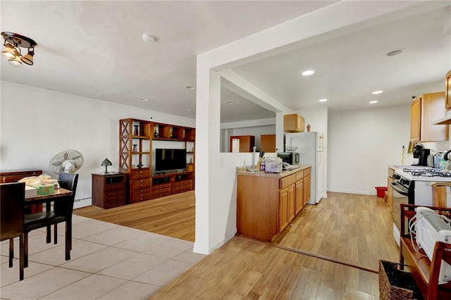 kitchen with gas stove, light wood-style flooring, recessed lighting, freestanding refrigerator, and light countertops