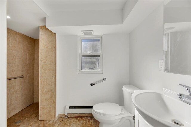 bathroom featuring a baseboard radiator, a tile shower, vanity, and toilet