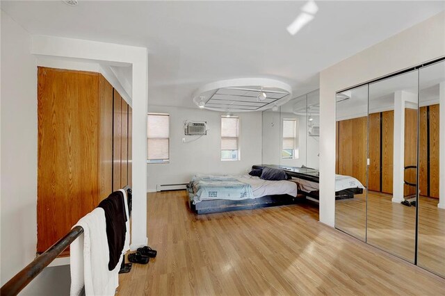 bedroom featuring baseboard heating, wood-type flooring, and a wall mounted AC