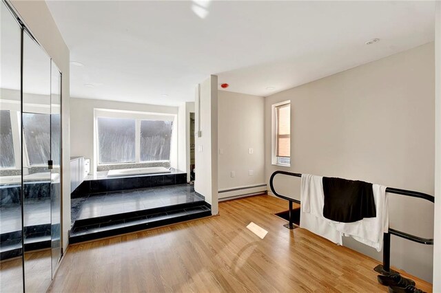 bedroom with light wood-type flooring and baseboard heating