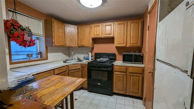 kitchen featuring tasteful backsplash, black range with gas stovetop, and sink