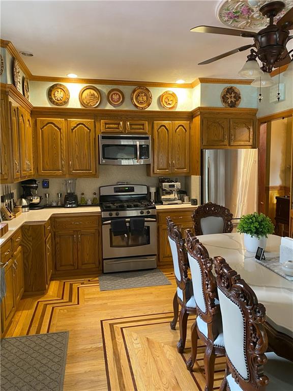 kitchen with ceiling fan, stainless steel appliances, and light wood-type flooring