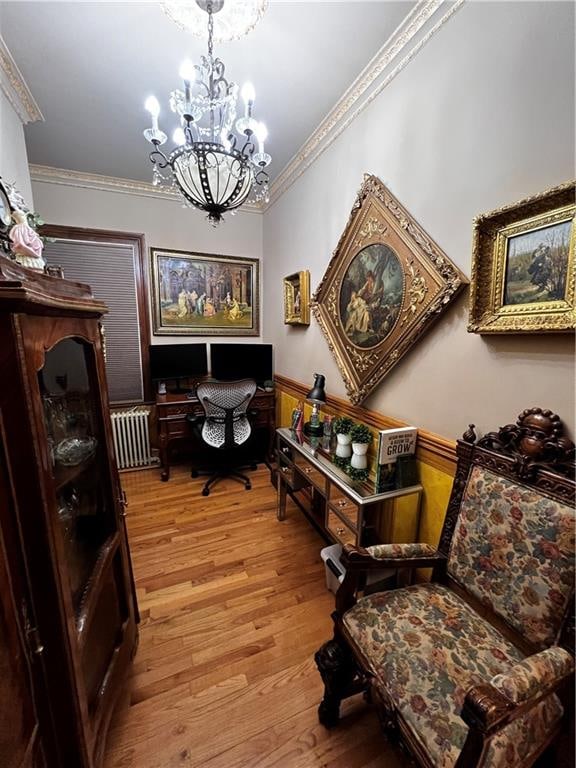 living area with ornamental molding, a chandelier, and light wood-type flooring