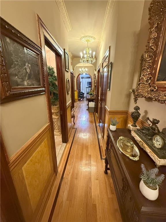 hallway with crown molding, light hardwood / wood-style flooring, and a chandelier