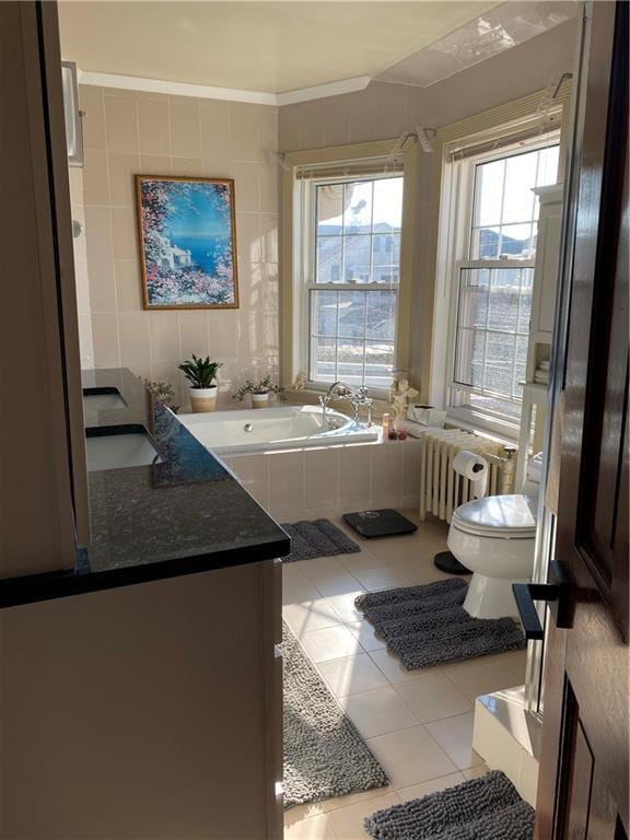 bathroom with tiled bath, toilet, tile patterned flooring, vanity, and radiator heating unit