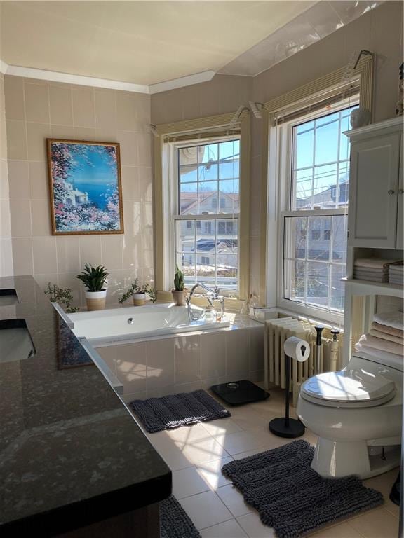 bathroom with tile walls, tiled tub, toilet, and tile patterned flooring