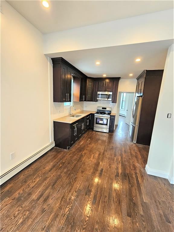 kitchen featuring a baseboard heating unit, appliances with stainless steel finishes, dark wood-type flooring, dark brown cabinetry, and sink