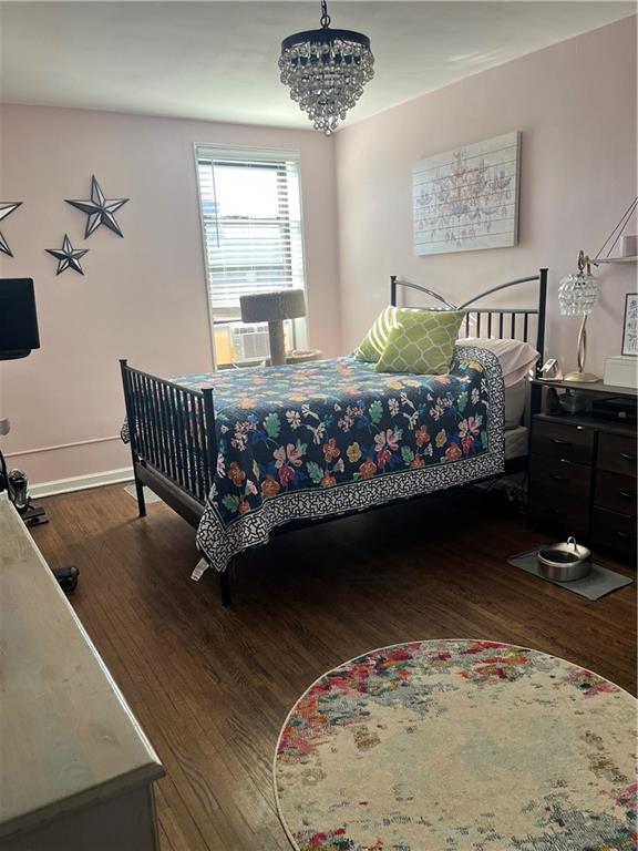 bedroom featuring an inviting chandelier, cooling unit, and dark hardwood / wood-style floors