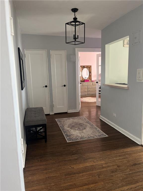 corridor with dark hardwood / wood-style floors and a chandelier