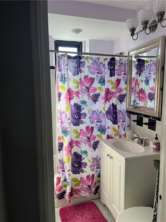 bathroom with walk in shower, vanity, toilet, and backsplash