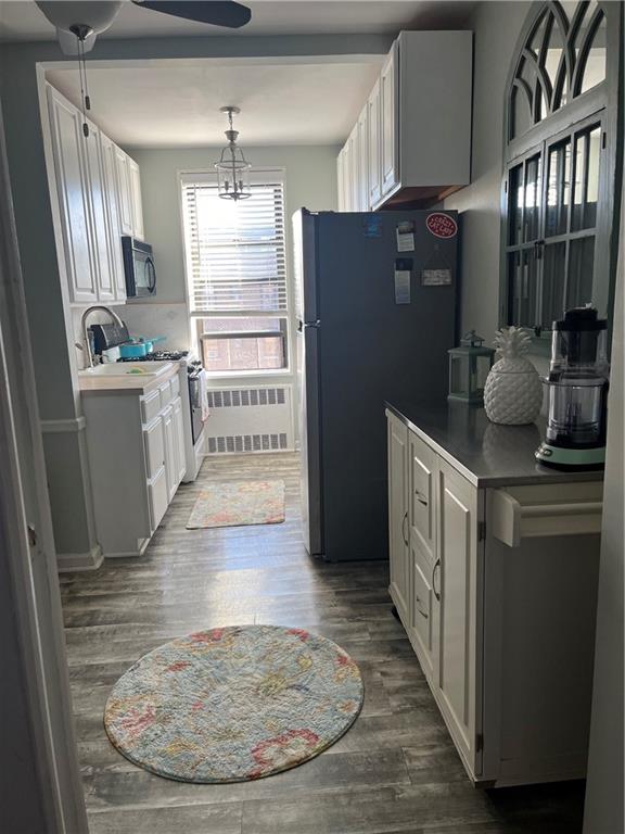 kitchen with ceiling fan with notable chandelier, decorative light fixtures, white cabinets, black appliances, and dark wood-type flooring