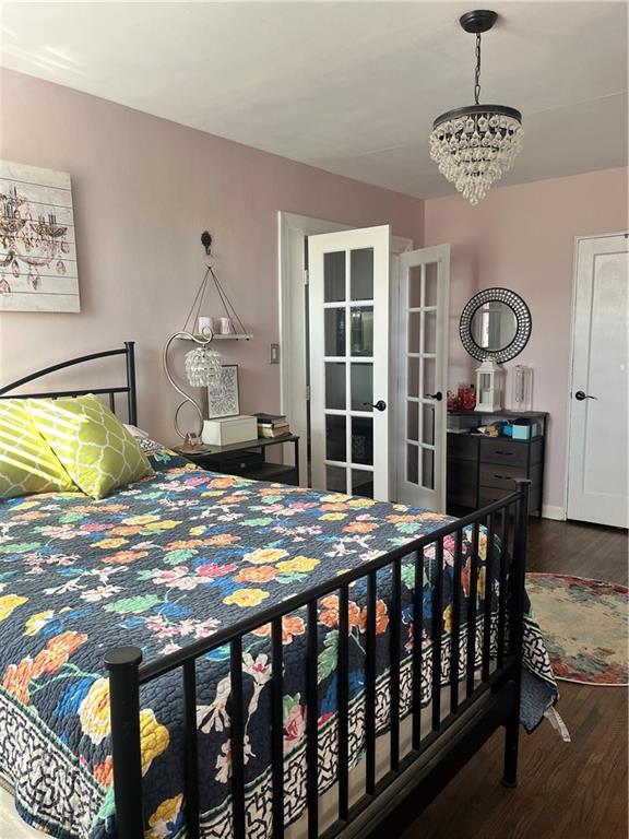 bedroom featuring hardwood / wood-style floors, an inviting chandelier, and french doors