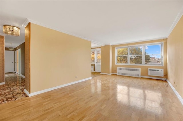 spare room featuring an inviting chandelier, light hardwood / wood-style flooring, an AC wall unit, ornamental molding, and radiator