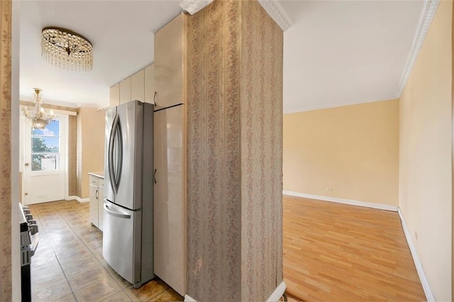 kitchen with light hardwood / wood-style flooring, a notable chandelier, ornamental molding, and stainless steel appliances