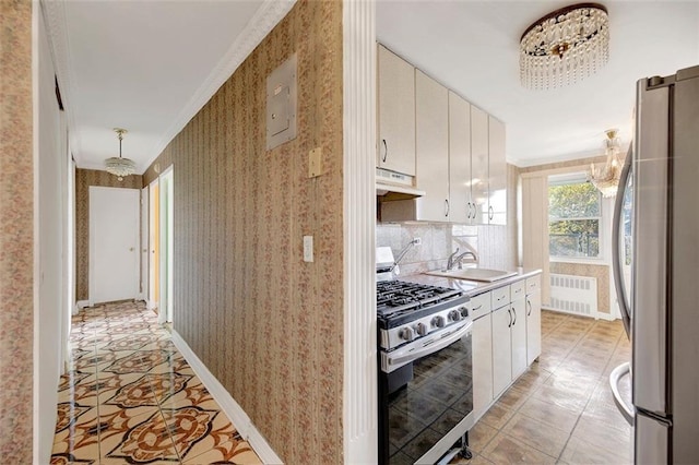 kitchen featuring stainless steel appliances, an inviting chandelier, a sink, under cabinet range hood, and wallpapered walls