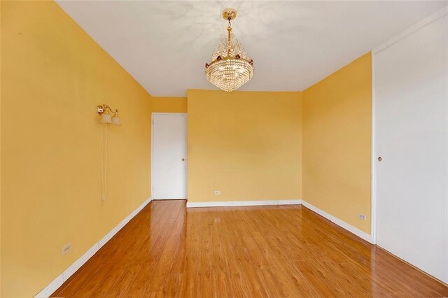 unfurnished room with hardwood / wood-style flooring and a notable chandelier