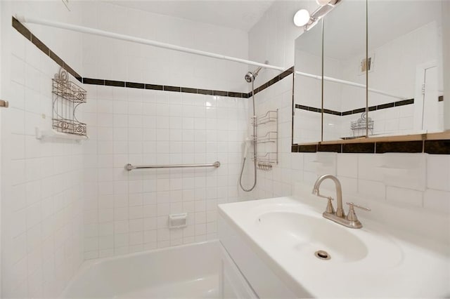 bathroom featuring tasteful backsplash, tile walls, tub / shower combination, and a sink