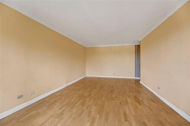 spare room featuring crown molding and light hardwood / wood-style flooring