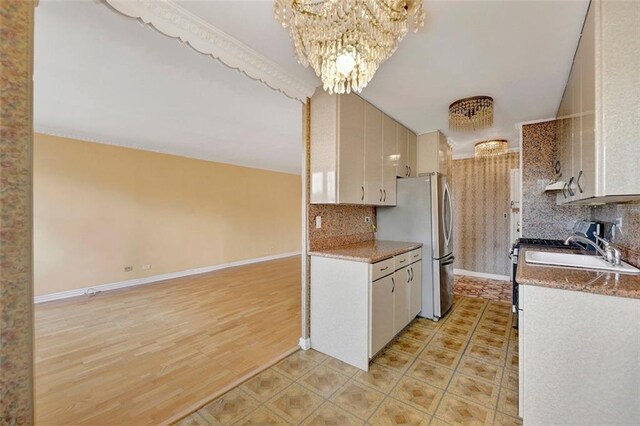 kitchen with tasteful backsplash, a notable chandelier, light hardwood / wood-style flooring, and sink